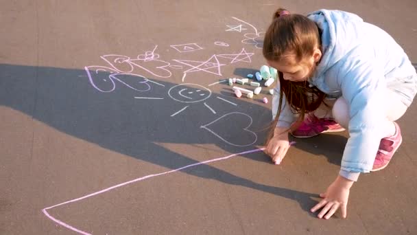 L'enfant dessine dans le parc. La fille dessine de la craie sur l'asphalte . — Video