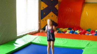 Trambolinde zıplayan küçük kız ve oyun merkezinde bungee.