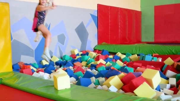 Маленькая девочка прыгает на батуте и банджи в игровом центре . — стоковое видео
