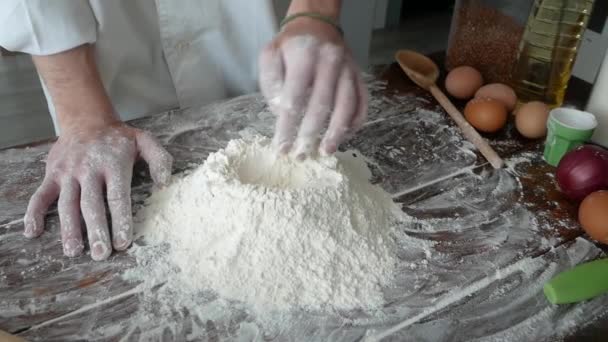 Шеф-повар разбивает яйцо в муку, чтобы сделать хлеб по традиционному рецепту. Человек, пекущий дома — стоковое видео