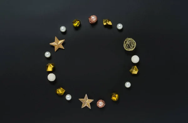 Festive round frame made of gold, sparkling and white ornaments, balls on a black background. Concept of Christmas and New Year backgrounds. Flat lay, copy space, top view