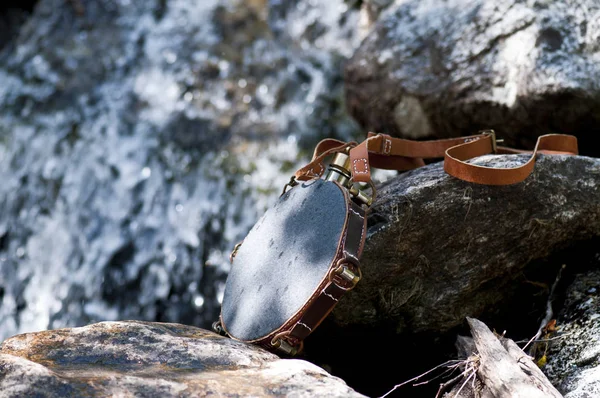 Şelalenin yanındaki kayalıklarda gri metal bir şişe.