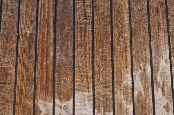 Dikey paralel çizgileri olan eski ıslak ahşap bir yat güvertesi.