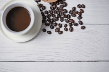 Bir fincan sade kahve ve kahve çekirdeği beyaz ahşap arka planda iyi esaslar. Üst görünüm.