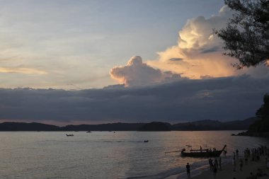 Güzel tropik sahil plaj, masmavi deniz, palmiye ağaçları ve turistler, Krabi, Ao Nang bakan Tayland. Güzel gün batımı ışık / görkemli kümülüs bulutlar gökyüzünde