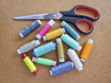 Ahşap bir arka plan üzerinde dikiş ve terzilik makas için bir rulo üzerinde çok renkli dikiş iplikleri. Kopyalama alanı ile