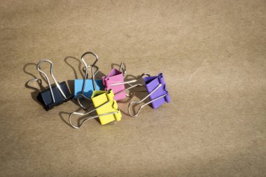 Kaba kahverengi kraft kağıt arka planda farklı renklerde kağıt klipleri. Kırtasiye. Metin için kopyalama alanı ile.