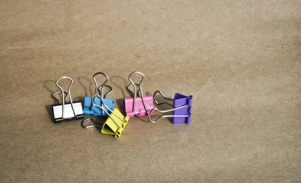 Kaba kahverengi kraft kağıt arka planda farklı renklerde kağıt klipleri. Kırtasiye. Metin için kopyalama alanı ile.