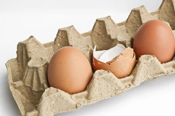 Carton packaging for eggs with broken eggshell and eggs on a light background. Organic concept