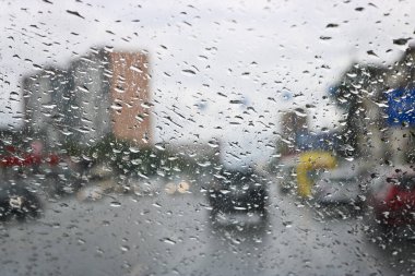 Arabanın ön camında yağmur damlaları var. Seçici odak. Yol daki arabanın camından manzara. Kötü görünürlük.