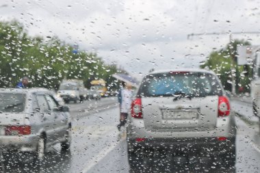 Arabanın ön camında yağmur damlaları var. Seçici odak. Yol daki arabanın camından manzara. Kötü görünürlük.