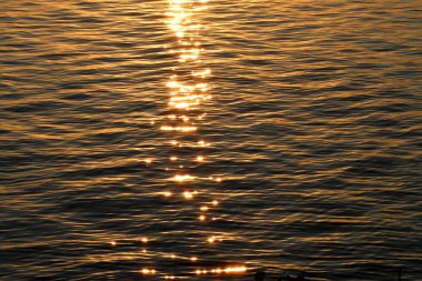 Gün batımında parlak güneş vurgular ile su üzerinde dalgalanmalar Doku.