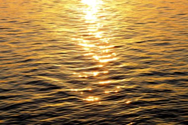 Gün batımında parlak güneş vurgular ile su üzerinde dalgalanmalar Doku.