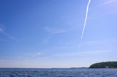 Gölün su yüzeyinin üzerinde cirrus bulutları ile mavi gökyüzüne karşı düzlemden dikey iz.