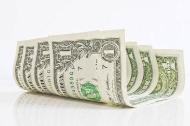 Hafif bir arka plan yakın çekim küçük bir kıvrılmış bir dolar banknotlar. Notların parlak bir yüzeye yansıması.