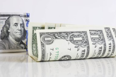 Hafif bir arka plan yakın çekim biraz kıvrılmış bir dolar banknotlar. Arka planda, Başkan Franklin 100 dolarlık banknotta. Notların parlak bir yüzeye yansıması.