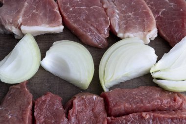 Ahşap bir yüzeyde kaba kesilmiş et ve soğan parçaları. Kötü kolesterol yiyeceği kavramı.