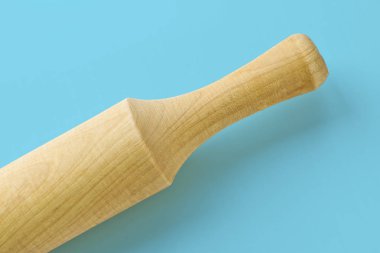 Mavi arka planda hamuru yuvarlamak için mutfak gereçleri merdanesi. Yemek pişirme araçları.