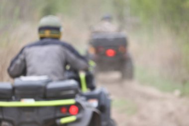 Bulanık görüntü. ATV 'li iki sürücü toprak yolda gidiyor. Açık hava aktiviteleri ve ekstrem spor kavramı.