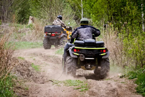 Seçici odaklanma. ATV 'li iki sürücü toprak yolda gidiyor. Açık hava aktiviteleri ve ekstrem spor kavramı.
