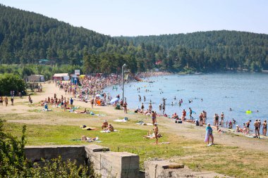 Miass, Rusya - Temmuz 2020: Turgoyak Gölü kıyısında bir turist kalabalığı. Gölde yüzen insanlar.