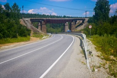 Otomatik tramvay Urzhumka nehri üzerindeki eski demiryolu köprüsünün altından geçiyor. Güney Ural, Rusya.