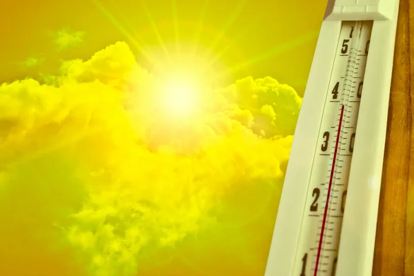 Heat wave - the concept of global warming. Summer heat. Thermometer  against a hot yellow sky and sun.