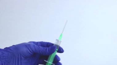 Mavi tıbbi eldivenli bir kadın elinde şırınga tutuyor. Yakın plan..