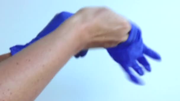Kobiece dłonie zakładają drugą niebieską rękawicę medyczną na dłoń. Zbliżenie. — Wideo stockowe