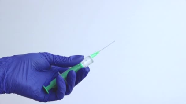 A female hand in a blue medical glove holds a syringe. Close-up. — Stock Video