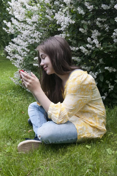 Tabletta számítógép szép kamasz lány ül a fűben, a Park. Fénykép — Stock Fotó