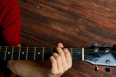 Ahşap arka plan üzerinde 6 telli gitar çalmak adamın elini. Konser poster için şablon