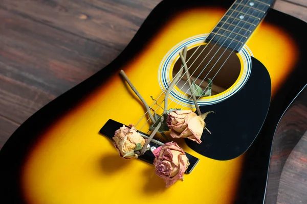 Gitara akustyczna z suszonych róż na drewnianym stole. Szablon dla koncert pamięci z miejscem na tekst — Zdjęcie stockowe