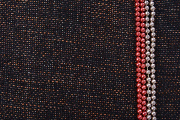 Abalorios hechos de perlas artificiales en el grosero hermoso tejido. Contexto — Foto de Stock