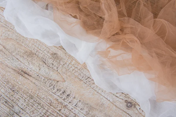 Laço de malha de tecido leve na mesa de madeira texturizada. Textura do tecido é lindamente drapeado — Fotografia de Stock