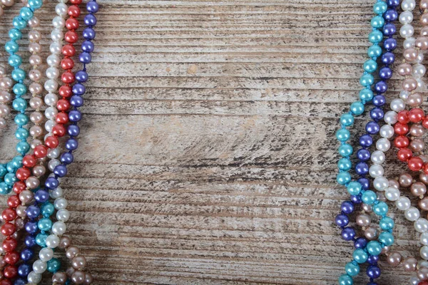 Frame of colorful beads on textured wooden background — Stock Photo, Image