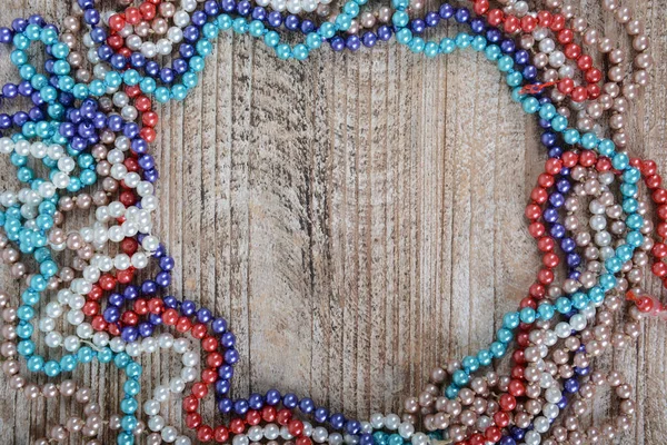 Frame of colorful beads on textured wooden background