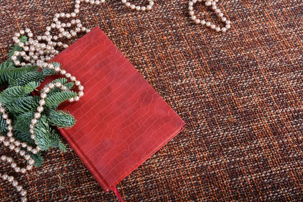 Weihnachtsdekoration mit Perlen, Perlen, Tannenzweigen und rotem Buch. — Stockfoto