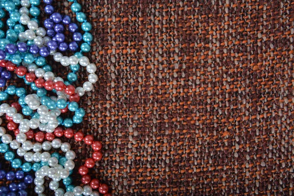 Collar de perlas en la textura de fondo de tela marrón. Composición izquierda . — Foto de Stock