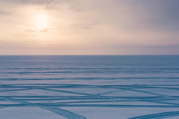 日没の空 雪の湖とスノーモービルトラックと最小限の冬の風景 — ストック写真