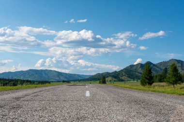 Arka planda bulutlar ve dağlar olan asfalt karayolu