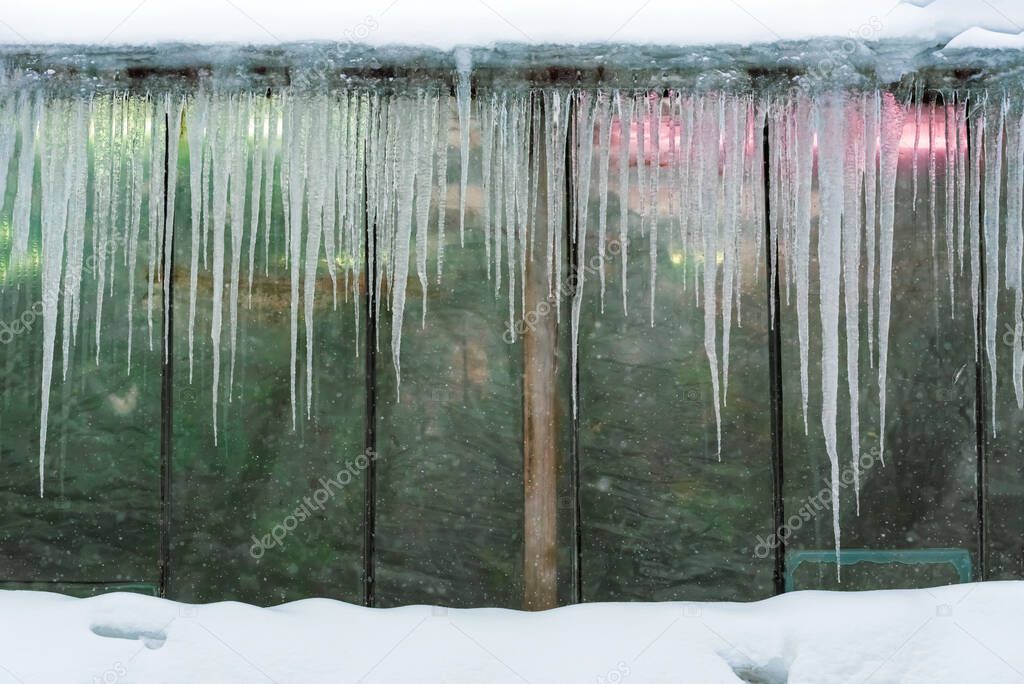 Icicle-covered cloudy greenhouse window, winter background