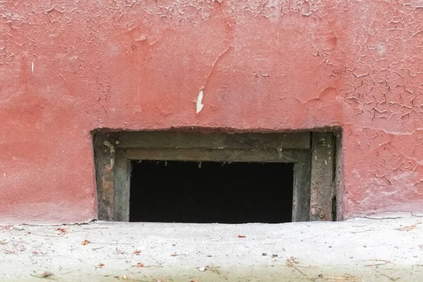 古い赤塗りの割れた壁の地下窓 — ストック写真