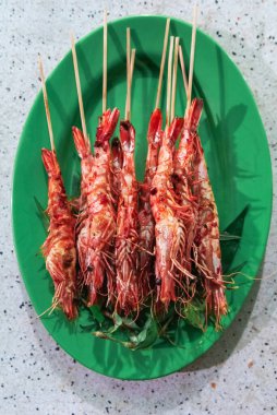 Çubuklarda ızgara Kral karidesleri tabakta yatıyor.