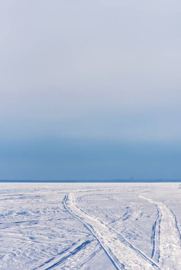 Kışın donmuş karla kaplı bir gölde kar arabası izleri.