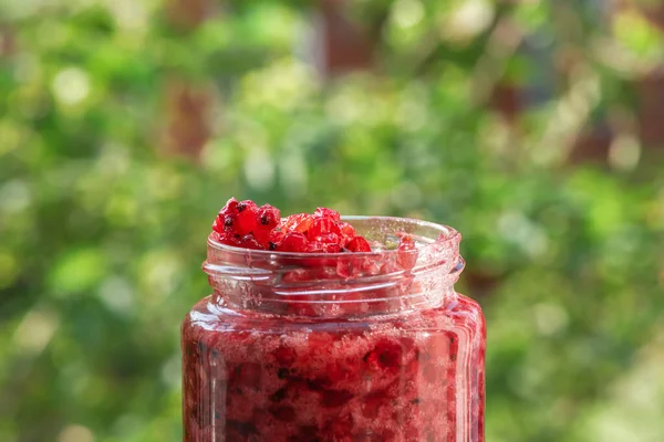 Bulanık yaz arka planında taze frenk üzümü reçeli kavanozu