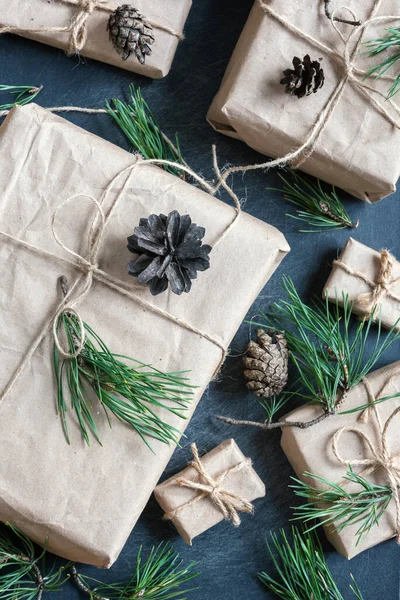 배경에는 크기의 크리스마스 선물이 종이에 소나무 가지와 솔방울로 장식되어 — 스톡 사진
