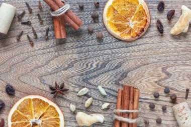 Ahşap arka planda sıcak şarap için malzemeler. Kurutulmuş portakal, tarçın, karabiber, karanfil, kuru zencefil, şarap mantarı. Üst görünüm, düz görünüm, kopyalama alanı.