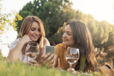 Güzel kadın parkta telefon kullanarak. Arkadaşları ve yaz konsepti.