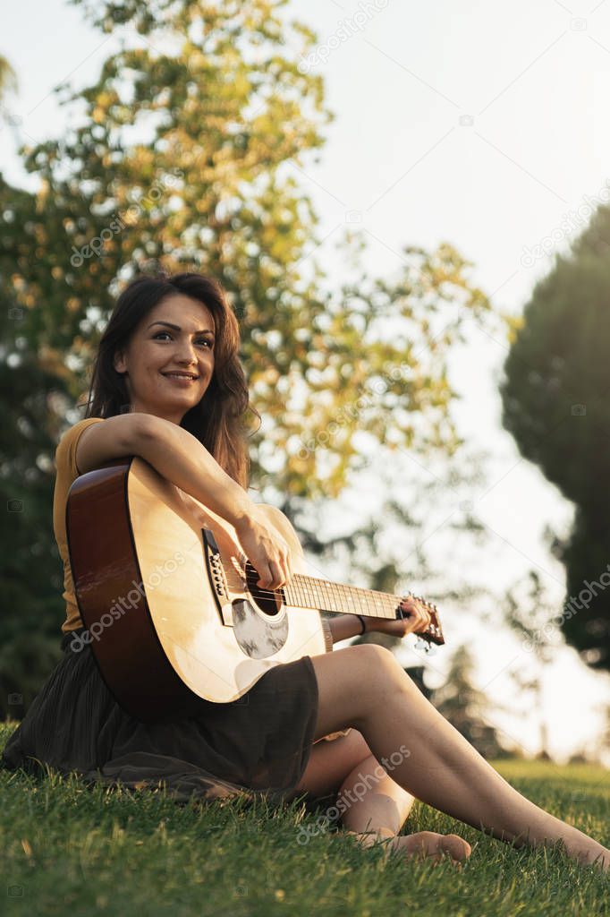 Beautiful woman playing guitar in the park.